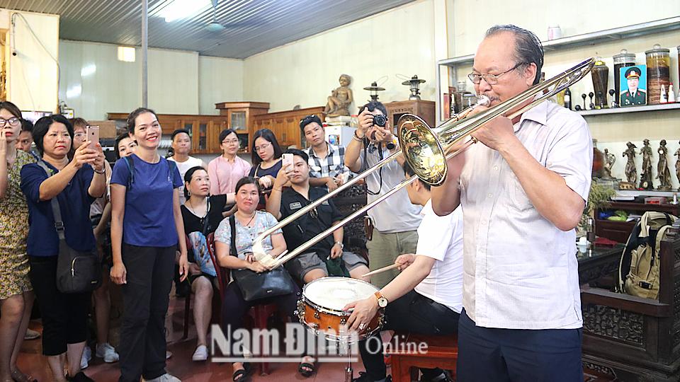 Du khách tham gia trải nghiệm tại làng nghề làm kèn đồng Phạm Pháo, xã Hải Minh (Hải Hậu).