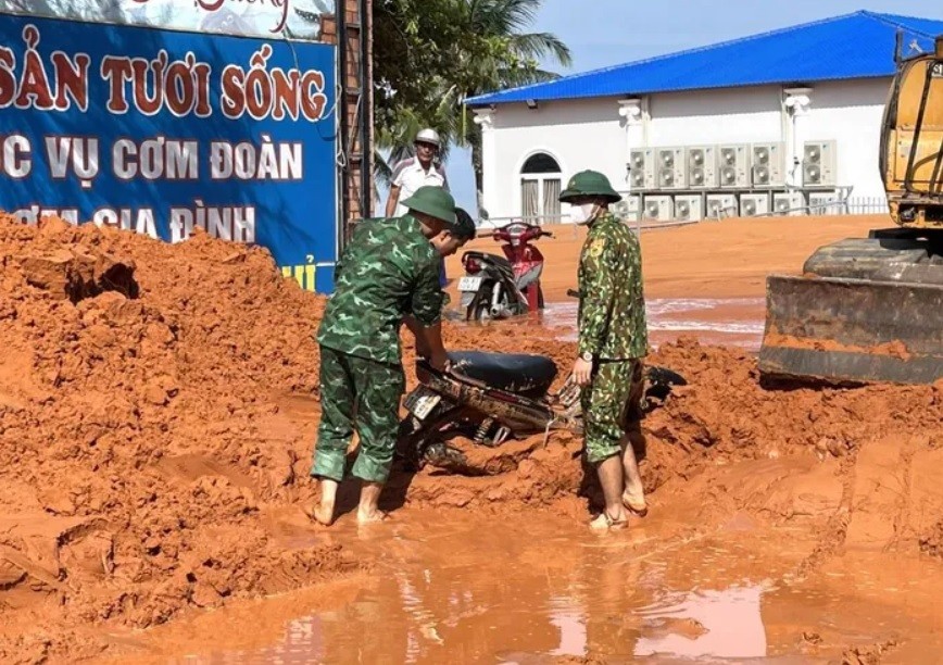 Cán bộ Đồn Biên phòng Mũi Né hỗ trợ tìm kiếm, di chuyển xe máy bị vùi lấp. Ảnh: Trung Thành