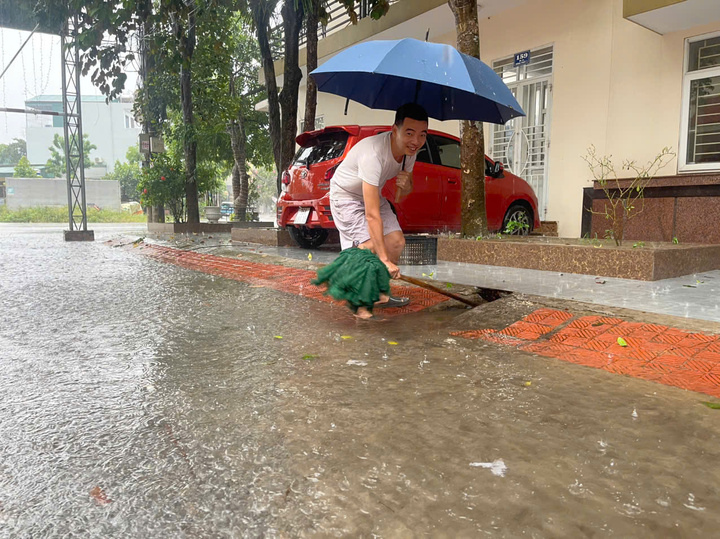 Ông Trần Văn Toàn, trú tại phố Lê Ngân, phường Hạc Thành đang thông cống để giúp nước thoát nhanh hơn. Ảnh: Hoàng Tuấn