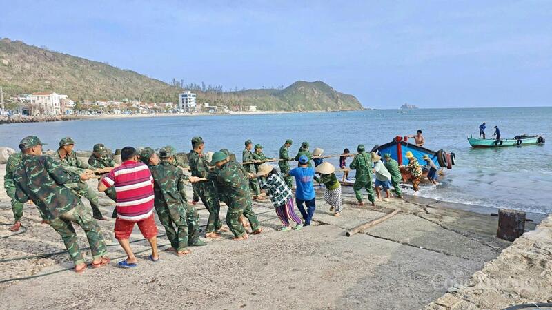 Các cán bộ, chiến sĩ hỗ trợ người dân đưa thuyền thúng lên bờ và hướng dẫn tàu thuyền trú tránh an toàn.